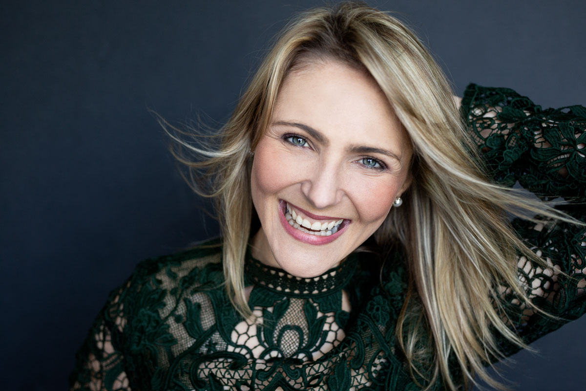 Portrait of a smiling woman wearing green lace dress by Joanna Zydel Bunbury Portrait Photographer